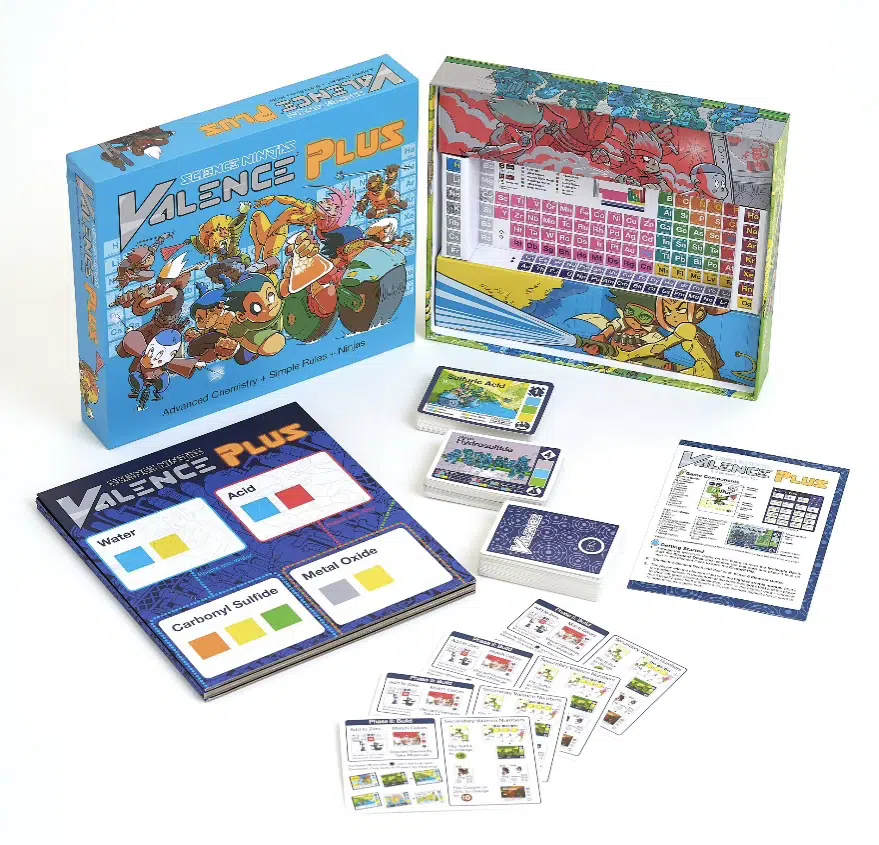 A chemistry-themed board game set is displayed, including a colorful game box, playing cards, a periodic table board, rules sheet, and category boards labeled Water, Acid, Carbonyl, and Metal Oxide.