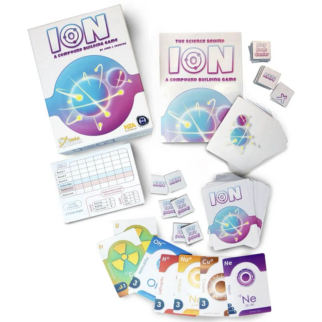 Board game "Ion: A Compound Building Game" displayed with box, instruction booklet, score sheets, element cards, and tiles arranged on a white surface.