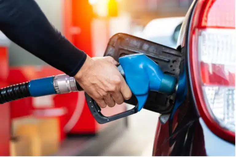 A person refuels a car at a gas station, holding a blue fuel nozzle inserted into the vehicle’s fuel tank, demonstrating how various functional groups of vehicles rely on efficient fueling.