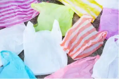 Several colorful plastic bags produced through polymerisation, some with stripes and others solid-colored, are spread out flat on a surface.